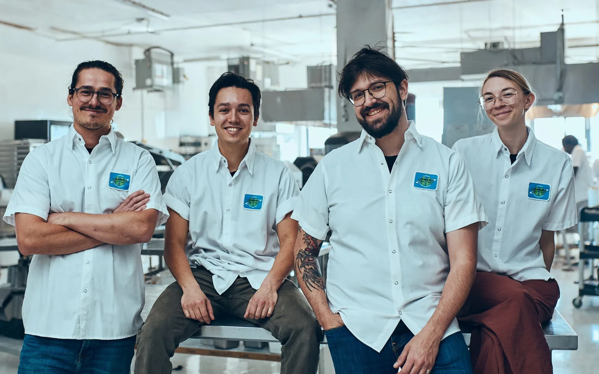 Group of people dressed in white uniforms posing for the camera at the Green Brothers offices