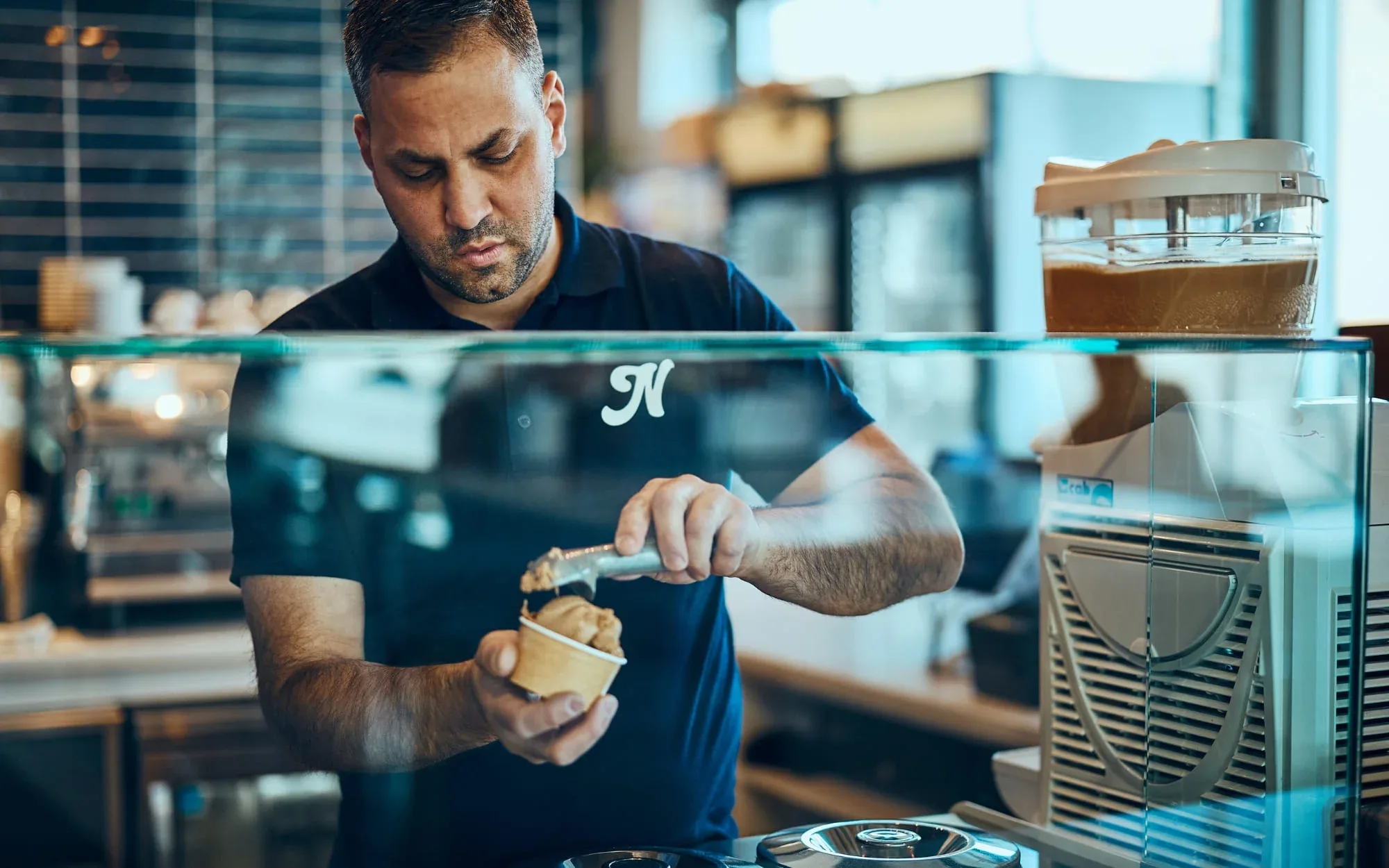 Man that is serving ice cream behind a counter