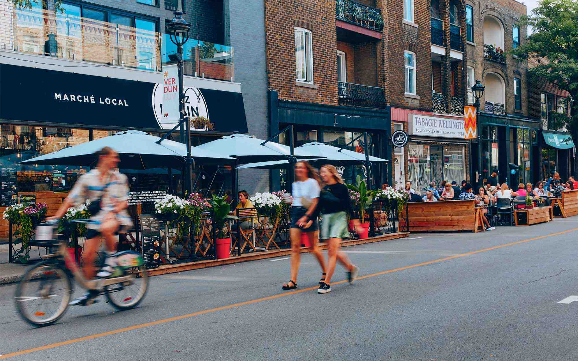 people walking in a street with restaurants and terraces